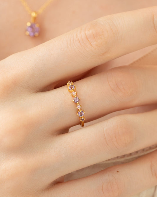 Gold ring with purple gemstones on a hand