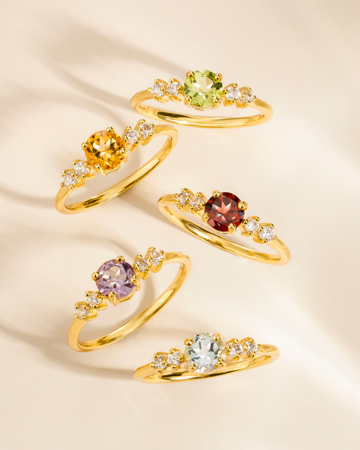 Set of gold rings with multicolored gemstones on a beige background