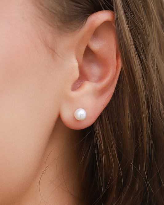 Close-up of an ear wearing a pearl earring with blurred background