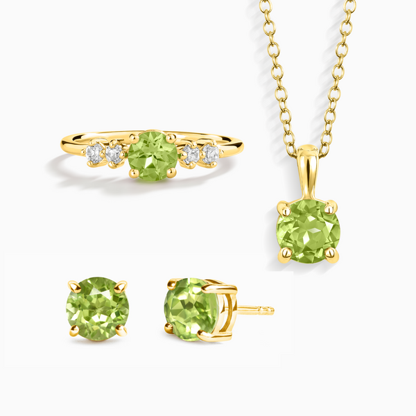 Gold jewelry set with green gemstones on a white background